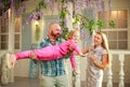 Happy parents with daughter have fun playing holding child on his hands, in courtyard summer family home