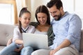 Happy parents with daughter relax on sofa using laptop Royalty Free Stock Photo