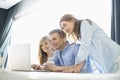 Happy parents with daughter using laptop at home