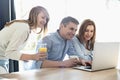 Happy parents with daughter using laptop at home