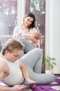 Happy parents. Father laying down on the floor and playing on tablet. Mother breast feed her baby boy. Royalty Free Stock Photo