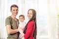 Happy parents father and mother playing with baby son at the in the morning on window background. Cheerful young family Royalty Free Stock Photo