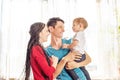 Happy parents father and mother playing with baby son at the on window background. Cheerful and modern young family Royalty Free Stock Photo
