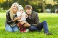 Happy parents with girl on green lawn in autumn park Royalty Free Stock Photo