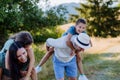 Happy parents giving their children piggyback ride in summer in nature. Royalty Free Stock Photo