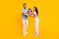 Happy parents holding daughter, girl spreading arms like plane, posing, having fun over yellow background, full length