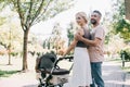 happy parents hugging and walking with baby carriage Royalty Free Stock Photo