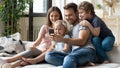 Happy parents with little children using phone together at home Royalty Free Stock Photo