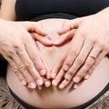 Happy parents make heart sign on pregnant woman's belly Royalty Free Stock Photo