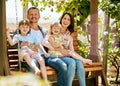 Happy parents make happy kids. Portrait of a family of four relaxing together on a garden swing. Royalty Free Stock Photo