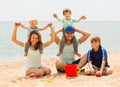 Happy parents playing with children at sea beach Royalty Free Stock Photo