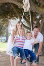 Happy parents pushing their children on a swing Royalty Free Stock Photo