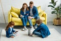 Happy parents sitting on sofa and looking at kids using laptop Royalty Free Stock Photo