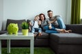 Happy parents and son having fun, tickling sitting together on the sofa, cheerful couple laughing, playing a game with their son, Royalty Free Stock Photo