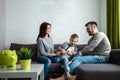 Happy parents and son having fun, tickling sitting together on the sofa, cheerful couple laughing, playing a game with their son, Royalty Free Stock Photo