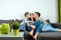 Happy parents and son having fun, tickling sitting together on the sofa, cheerful couple laughing, playing a game with their son, Royalty Free Stock Photo