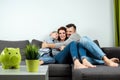 Happy parents and son having fun, tickling sitting together on the sofa, cheerful couple laughing, playing a game with their son, Royalty Free Stock Photo