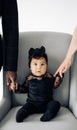 Happy parents stand near their baby daughter from interracial marriage and hold her hands