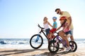 Happy parents teaching children to ride bicycles on sandy beach Royalty Free Stock Photo