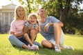 Happy parents with their child having fun on green grass. Spending time in nature Royalty Free Stock Photo