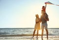Happy parents and their child playing with kite on beach near sea. Spending time in nature Royalty Free Stock Photo