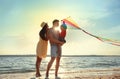 Happy parents and their child playing with kite on beach near sea. Spending time in nature Royalty Free Stock Photo