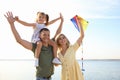 Happy parents with their child playing with kite on beach. Spending time in nature Royalty Free Stock Photo