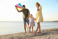 Happy parents with their child playing with kite on beach. Spending time in nature Royalty Free Stock Photo