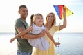 Happy parents with their child playing with kite on beach. Spending time in nature Royalty Free Stock Photo