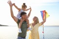 Happy parents with their child playing with kite on beach. Spending time in nature Royalty Free Stock Photo