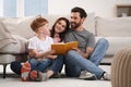 Happy parents with their child reading book on floor at home Royalty Free Stock Photo