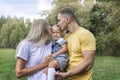 Happy parents with their little daughter in the park on a sunny summer day. Laughing young woman with a man and a child in jeans