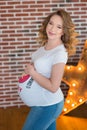 Happy parents-to-be couple looking at a cute red baby shoes for their unborn child, indoors studio portrait Royalty Free Stock Photo