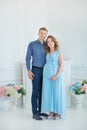 Happy parents-to-be couple looking at a cute red baby shoes for their unborn child, indoors studio portrait Royalty Free Stock Photo