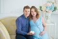 Happy parents-to-be couple looking at a cute red baby shoes for their unborn child, indoors studio portrait Royalty Free Stock Photo