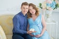 Happy parents-to-be couple looking at a cute red baby shoes for their unborn child, indoors studio portrait Royalty Free Stock Photo