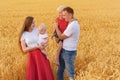 Happy parents with two children walking through wheat field. Weekend with family outsides