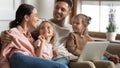 Happy parents with two little daughters using laptop at home Royalty Free Stock Photo