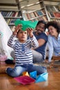 Happy parents watching their cute little son while he is sitting on the floor at home and playing with paper boats. Family, home, Royalty Free Stock Photo