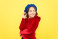 Happy parisian child in french beret hat and elegant red dress on yellow background, kid retro fashion
