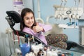 Happy patient girl showing thumbs up at dental clinic office. Medicine, stomatology and health care concept