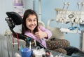 Happy patient girl showing thumbs up at dental office. Medicine, stomatology and health care concept