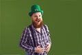 Happy Patrick`s Day. Funny fat bearded man in a green hat is laughing on a green background.