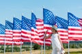 Patriotic child standing in white dress near american flags and waving hand