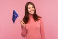 Happy patriotic woman with brown hair holding eu flag in hand looking at camera with toothy smile, patriotism, flag day