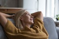 Happy peaceful middle aged lady relaxing on home sofa