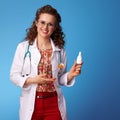 Happy pediatrist doctor recommending nasal spray on blue