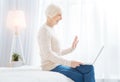 Happy pensioner waving while having a video talk with her daughter