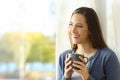 Happy pensive woman looks at side beside a window