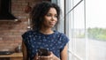 Happy pensive young African American woman with smartphone looking away Royalty Free Stock Photo